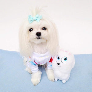 Small white dog with a bow tie next to a plush toy on a blue surface at Pet Servo