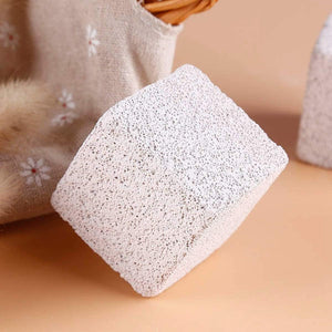 Square pumice stone on a beige surface with a floral towel in the background at Pet Servo