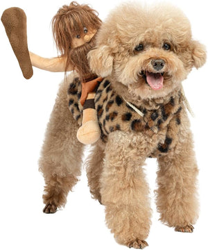 A fluffy light tan dog wearing a leopard-print pet costume with a plush doll riding on its back, photographed against a plain white background.
