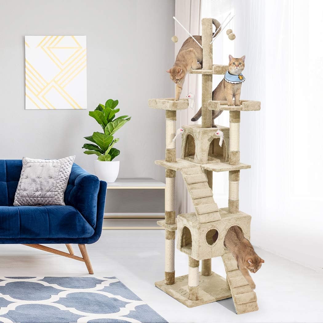 A tall beige cat tree with multiple levels, sisal-wrapped scratching posts, climbing stairs, and cat houses, shown in a bright living room with two cats using it. A blue velvet sofa, potted plant, and wall art are visible in the background at Pet Servo