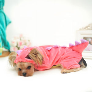 Dog wearing a pink dinosaur costume on a white background at Pet Servo