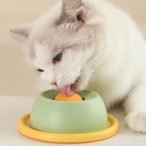 Cat eating from a green bowl with a yellow base on a beige surface at Pet Servo