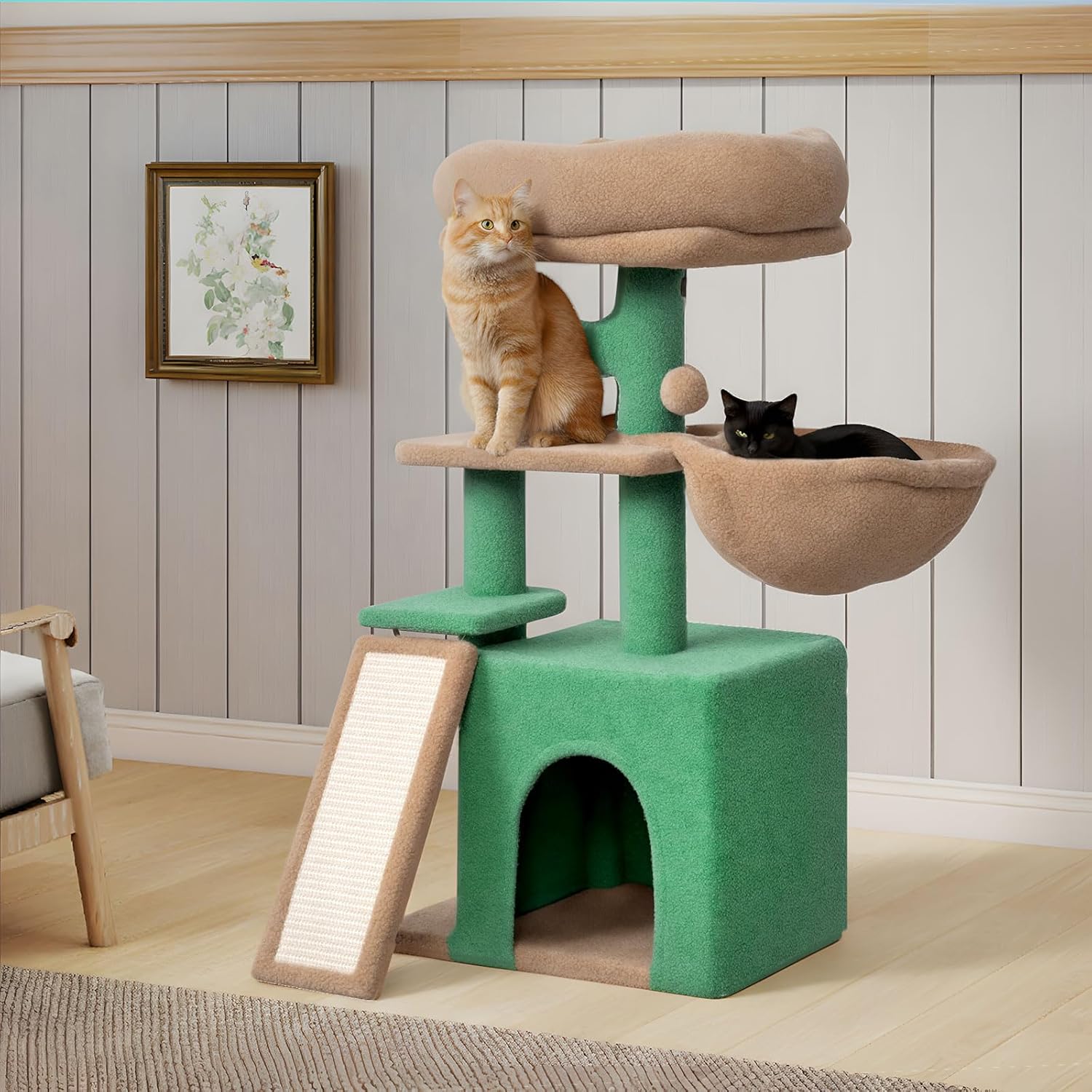 A green and beige cat tree with two cats, one orange tabby sitting on the middle perch and one black cat resting in the top hammock, set in a room with light wood floors and paneled walls at Pet Servo