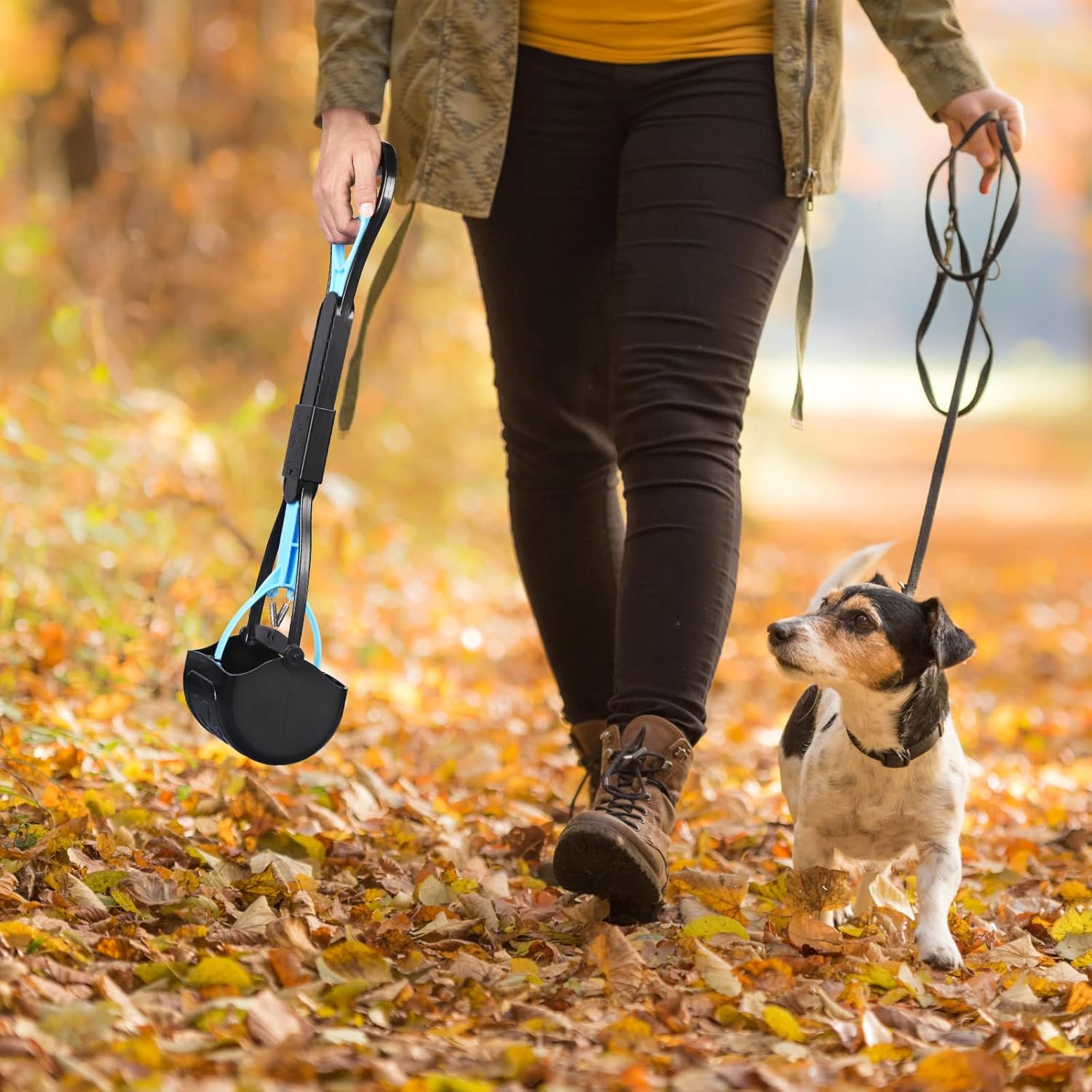 Person walking a dog on a leash with a portable dog waste bag holder in an autumn setting at Pet Servo