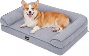 A corgi dog lies on a raised gray pet bed with armrests, photographed on a clean white background. A small black Pooky brand label is visible on the front edge of the bed at Pet Servo