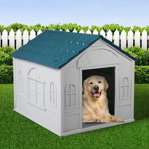 Dog sitting in a white doghouse with a blue roof on grass, white picket fence, and green bushes in the background at Pet Servo