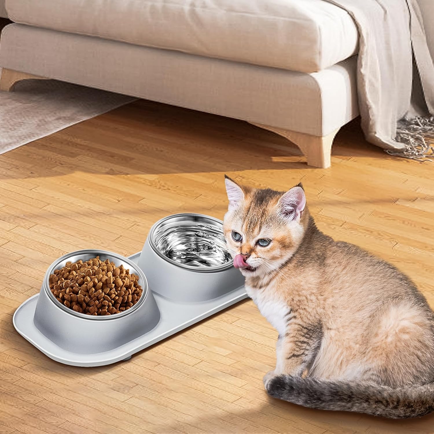 Cat sitting next to a double pet feeder with food on a wooden floor at Pet Servo