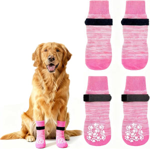 Dog wearing pink dog boots with paw prints and a set of four additional pink dog boots on a white background at Pet Servo