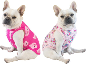 Two dogs wearing pink sleeveless outfits with different patterns on a white background at Pet Servo