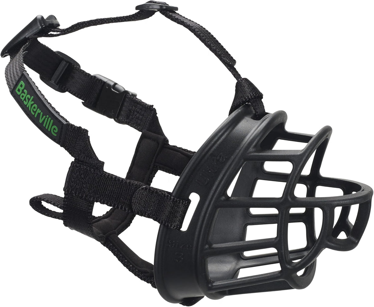 A black dog muzzle with a wire cage face guard and adjustable black straps, featuring the green 'BakerVille' brand name on one strap, shown on a plain white background.