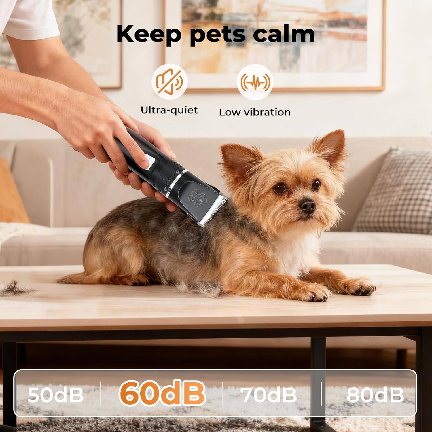 A small tan and gray dog sits on a wooden table in a living room while a person uses a black pet grooming clipper. Text at the top says 'Keep pets calm' with icons for ultra-quiet operation and low vibration at Pet Servo