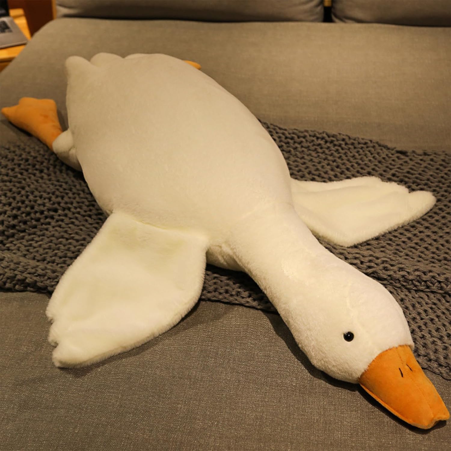 Plush toy goose lying on a textured surface at Pet Servo