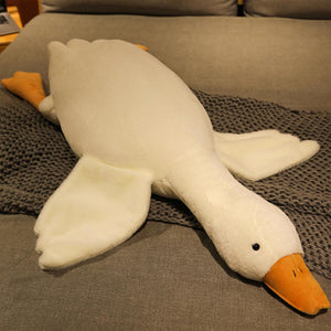 Plush toy goose lying on a textured surface at Pet Servo