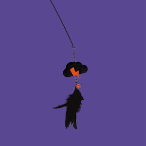A Halloween-themed cat toy featuring a black cloud-shaped collar with an orange lightning bolt, a small orange ball, and a dangling black cat silhouette, shown against a solid purple background at Pet Servo