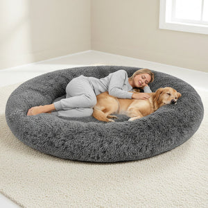 Woman and dog relaxing on a large fluffy gray pet bed in a room with a window at Pet Servo