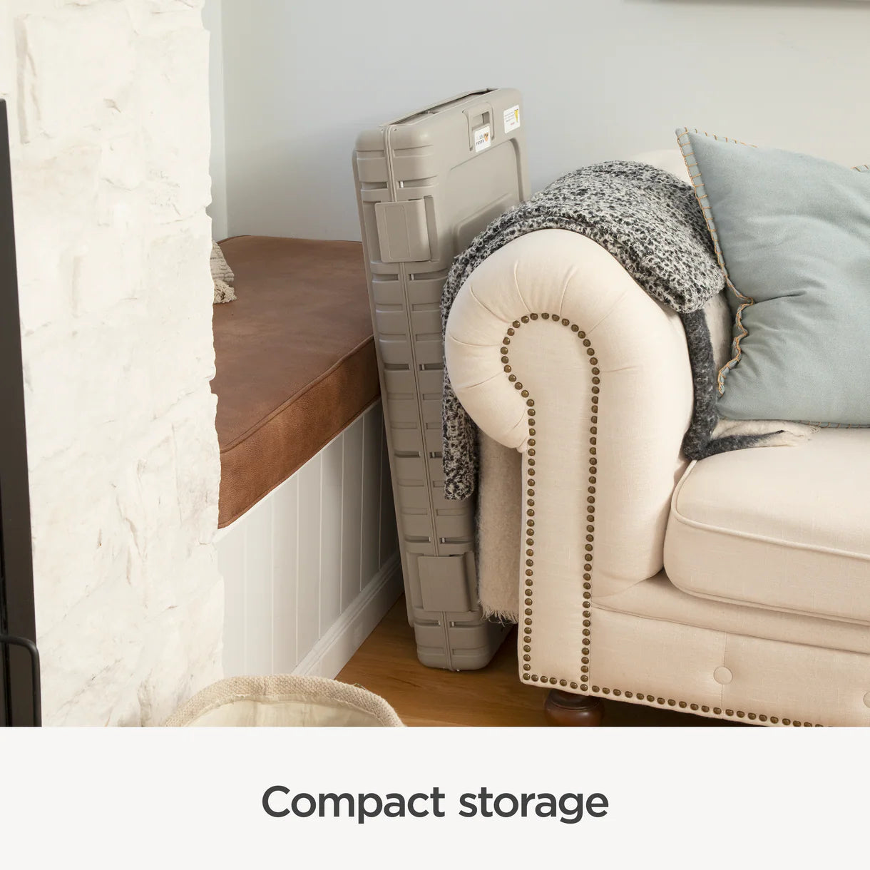 Foldable storage bench against a wall next to a sofa with cushions.