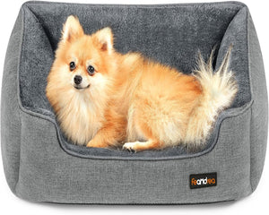 Small dog lying on a gray pet bed with a visible brand logo.