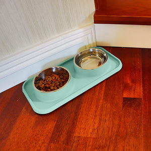 Pet feeding station with two metal bowls on a green tray on a wooden floor at Pet Servo