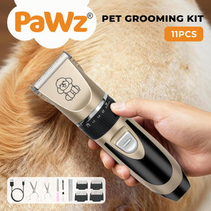 A handheld pet grooming clipper being used on a dog's fur, with a human hand holding the device. The clipper is beige and black with a small dog icon printed on the blade cover at Pet Servo