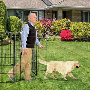 An older man walks through a black metal gate in a backyard while a golden retriever dog watches him. The scene is set on a green lawn in front of a house with shrubs and flowers at Pet Servo