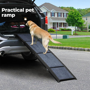 A black textured pet ramp with a yellow Labrador retriever standing on it to climb into the open trunk of a black SUV, with a suburban house and lawn in the background. White text in the top left reads 'Practical pet ramp' at Pet Servo