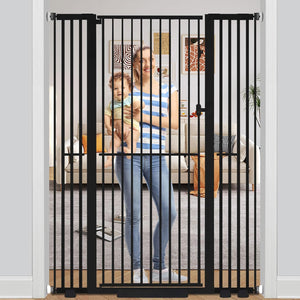 Woman holding a child behind a black metal gate in a home setting