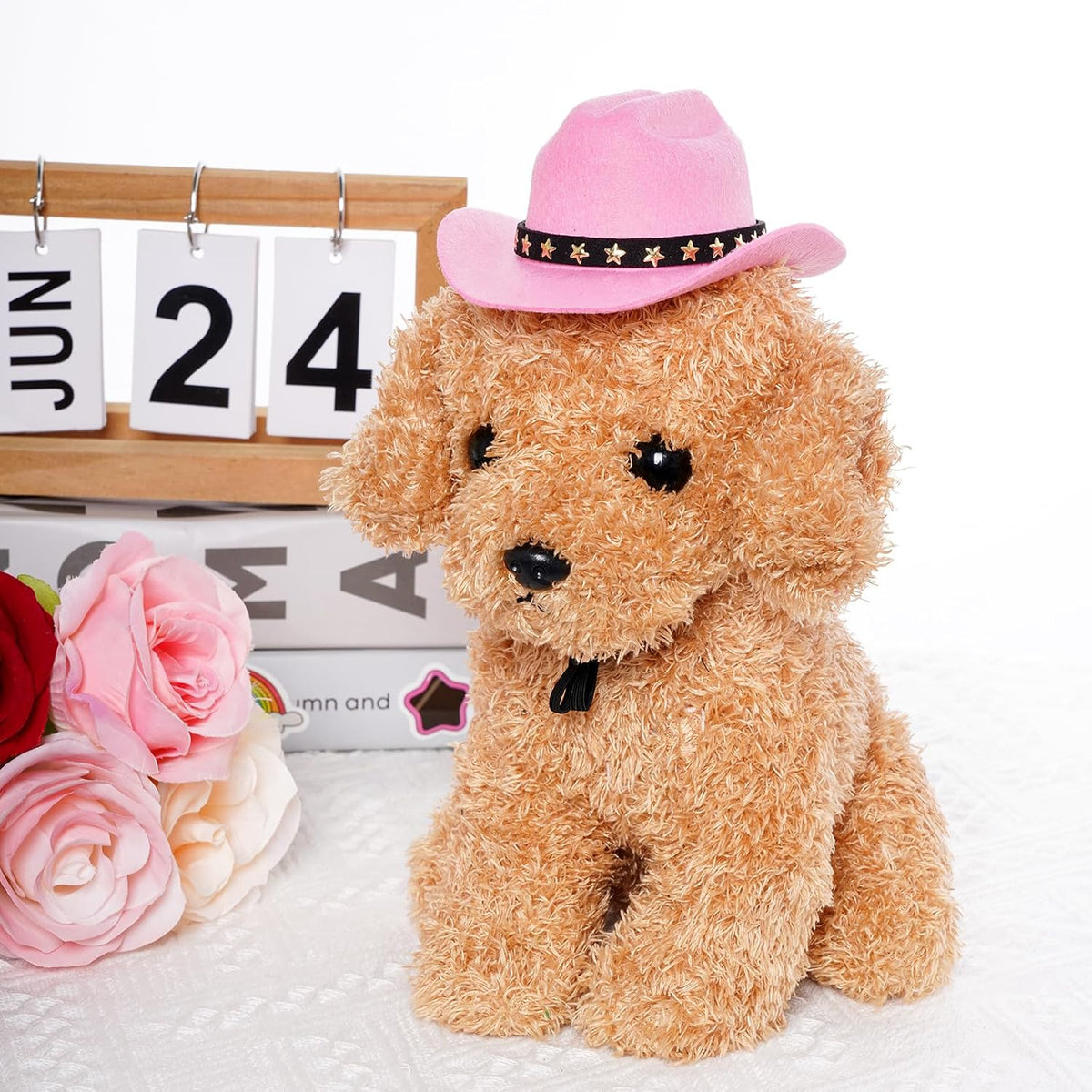 A fluffy light brown plush puppy wearing a pink cowboy hat with a black band and gold stars, posed on a white textured surface with decorative flowers and a calendar in the background at Pet Servo