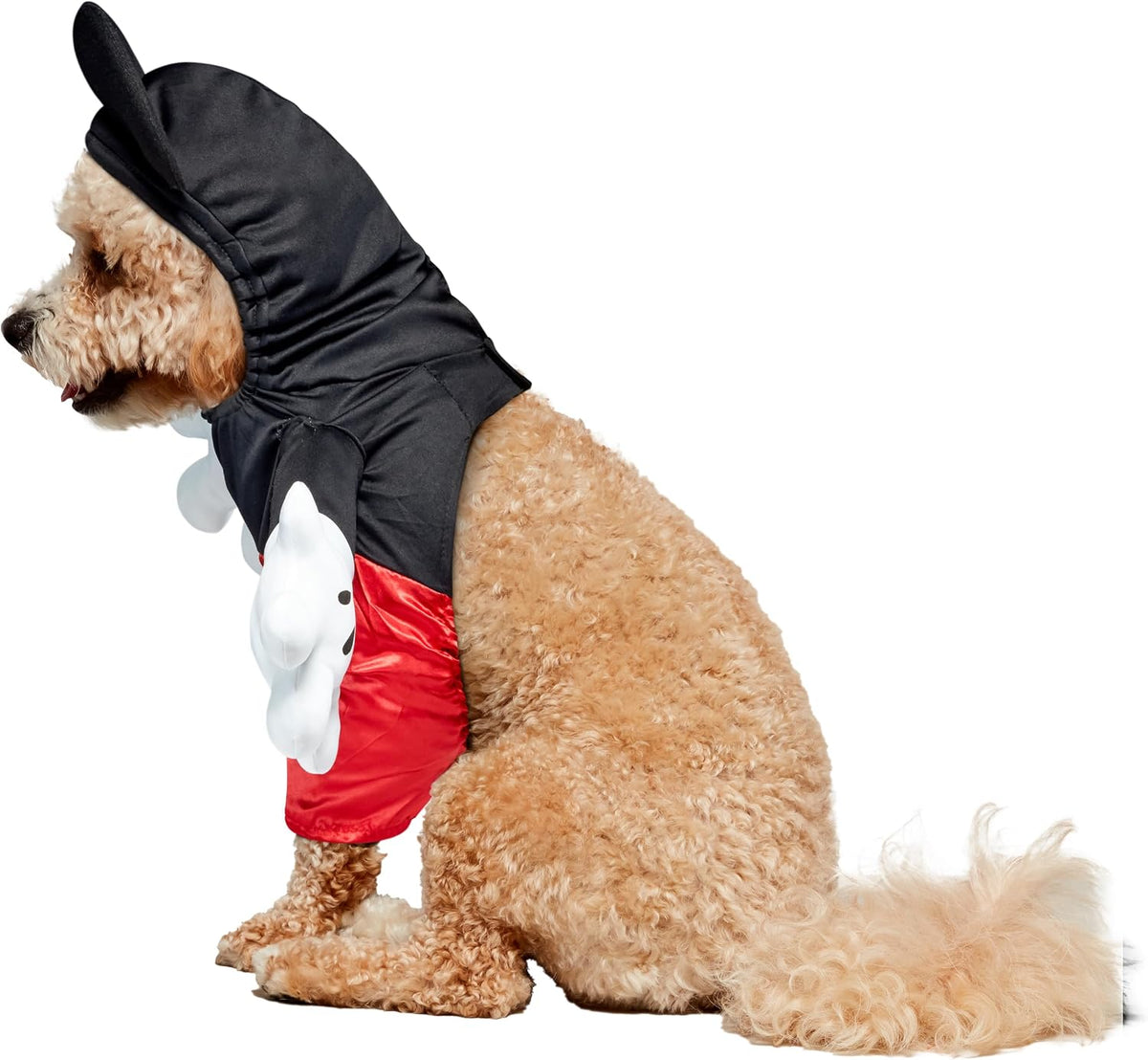 A small tan dog wearing a Mickey Mouse-inspired costume, including a black hood with ear-like flaps, a red shorts section, and white glove details, photographed on a plain white background at Pet Servo