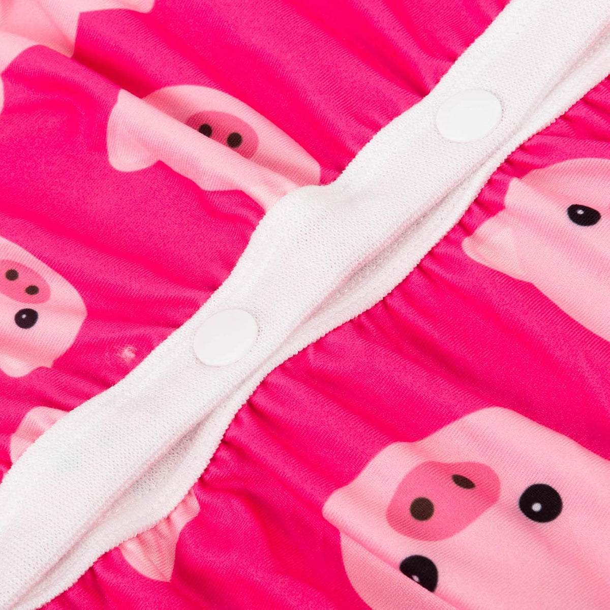 Close-up of a bright pink fabric product with a repeating cartoon pig face print and a white snap-button closure at Pet Servo