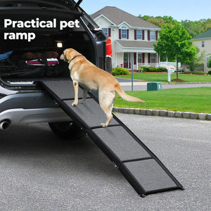 A tan Labrador retriever uses a black and gray foldable pet ramp to get into the trunk of a silver SUV on a suburban street. The text 'Practical pet ramp' is visible in the top left corner at Pet Servo