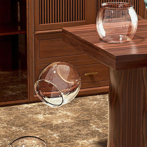 Glass vase on a wooden surface with a wooden cabinet in the background at Pet Servo