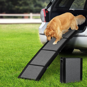 A golden retriever dog is climbing a black pet car ramp positioned beside an open SUV door on a green lawn, with a folded version of the ramp standing nearby at Pet Servo