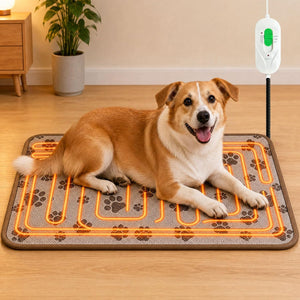 A tan and white dog lies on a rectangular heated pet mat with an orange heating circuit visible beneath it. The mat has a gray background with brown paw-print patterns.