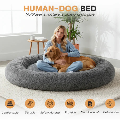 Woman sitting on a large gray 'Human-Dog' bed with a dog, in a home setting at Pet Servo