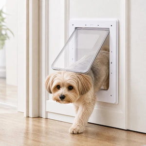 A small fluffy dog walks through a white pet door with a clear angled flap, set in a clean indoor room with light wood flooring and cream walls at Pet Servo