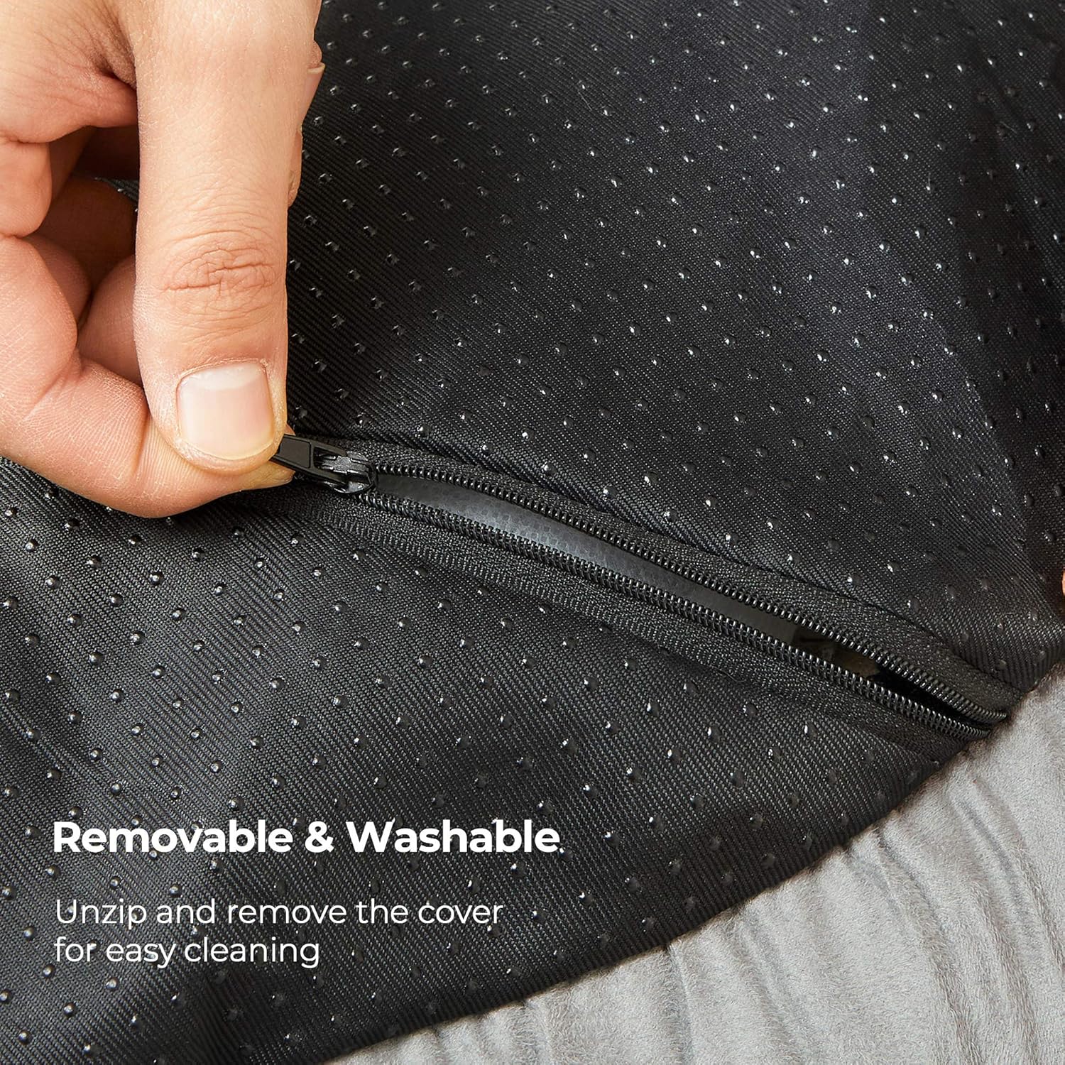 Hand unzipping a black jacket with text indicating it is removable and washable at Pet Servo