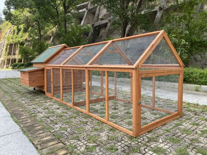 Wooden chicken coop on a stone path with trees and a building in the background at Pet Servo