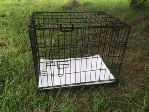 Black metal dog crate with a white towel on grass at Pet Servo