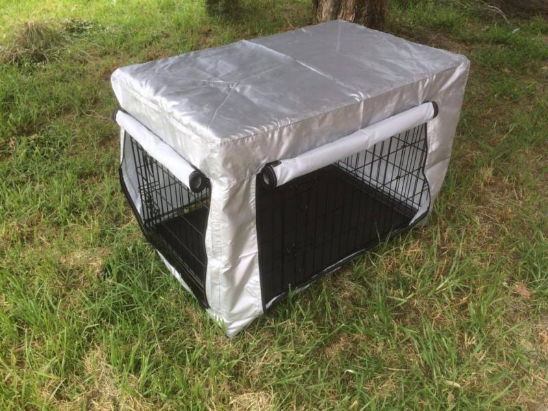 Black pet crate with a silver cover on a grassy ground at Pet Servo