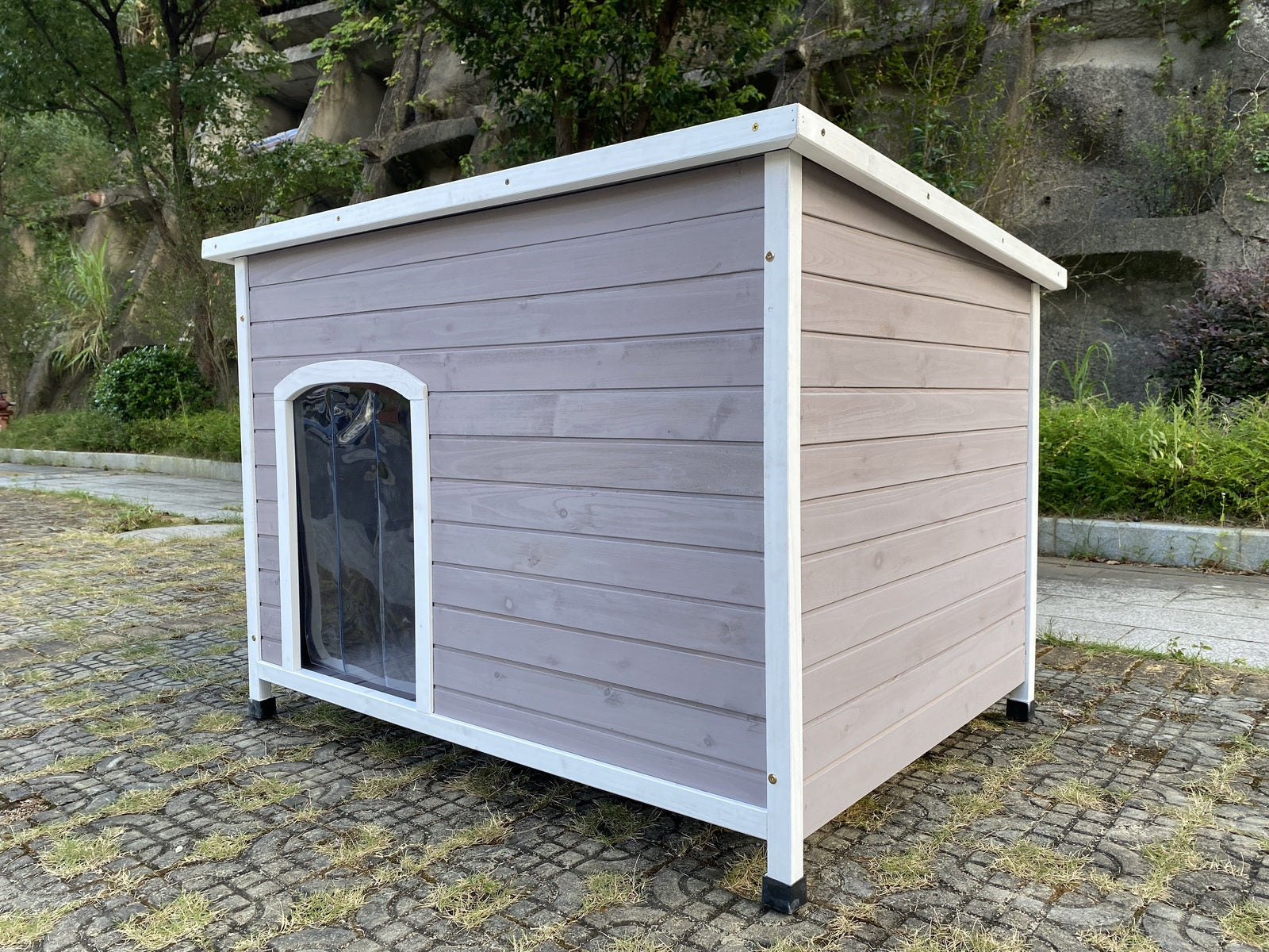 Wooden dog house with a white border on a stone pavement at Pet Servo