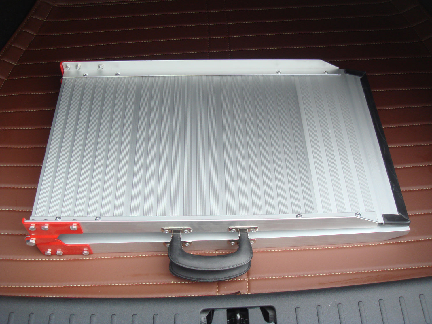 Metal toolbox with a red handle on a brown surface at Pet Servo