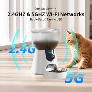 White automatic pet feeder with a bowl on a light wood floor next to an orange tabby cat. The image includes text overlays 'Compatible With 2 at Pet Servo
