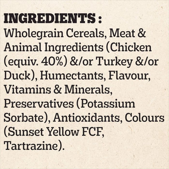 A text panel on a light beige textured background listing ingredients, including wholegrain cereals, meat and animal ingredients such as chicken and turkey, humectants, flavour, vitamins & minerals, preservatives, and antioxidants like Sunset Yellow FCF and Tartrazine.