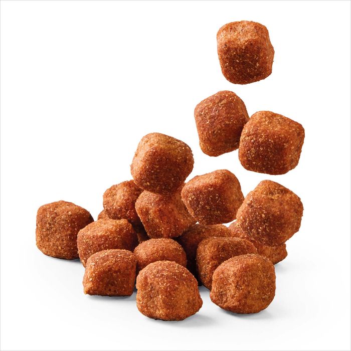 A pile of small, irregularly shaped brown coated pieces, some of which are floating above a main cluster, photographed on a clean white background.