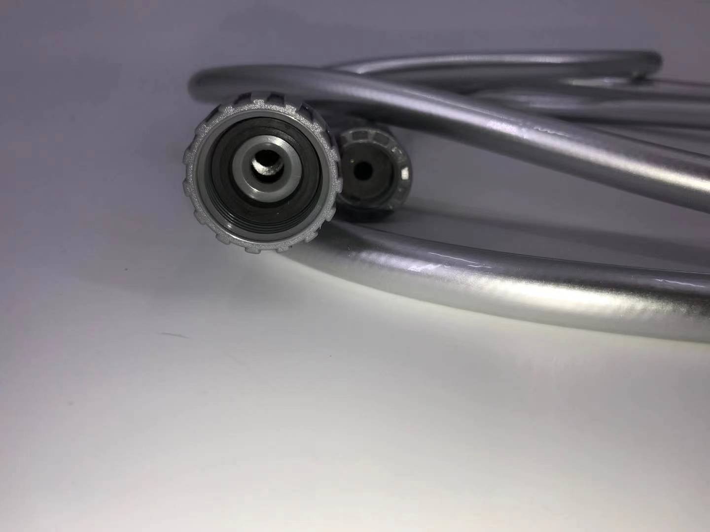 Close-up of a coiled metal cable with connectors on a gray background at Pet Servo