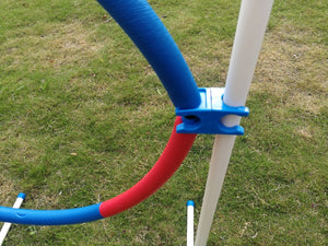 Colorful pool noodles attached to a white pole on grass at Pet Servo