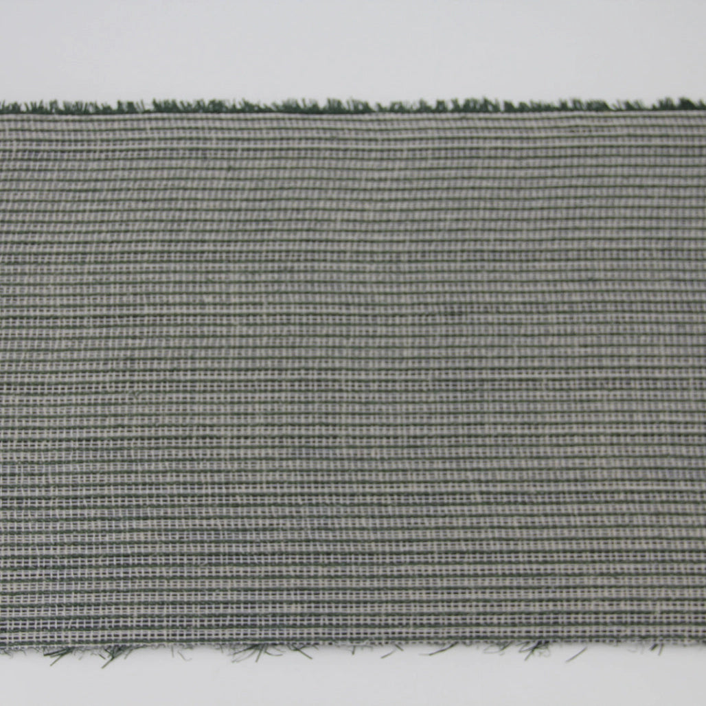 A close-up of a woven fabric or carpet sample with a tight gray and white crosshatch pattern and short dark green fibers visible along the top and bottom edges, shown against a plain white background at Pet Servo