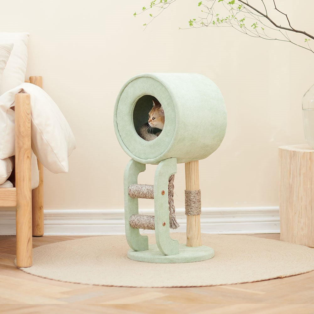 Cat playing inside a green cat tree with wooden elements on a light wood floor at Pet Servo
