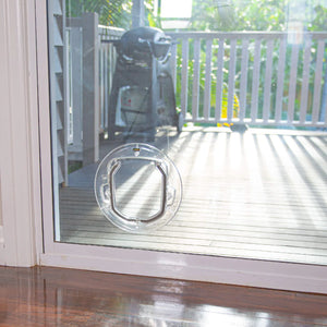 Pet door on a glass door with a view of a patio and motorcycle outside.