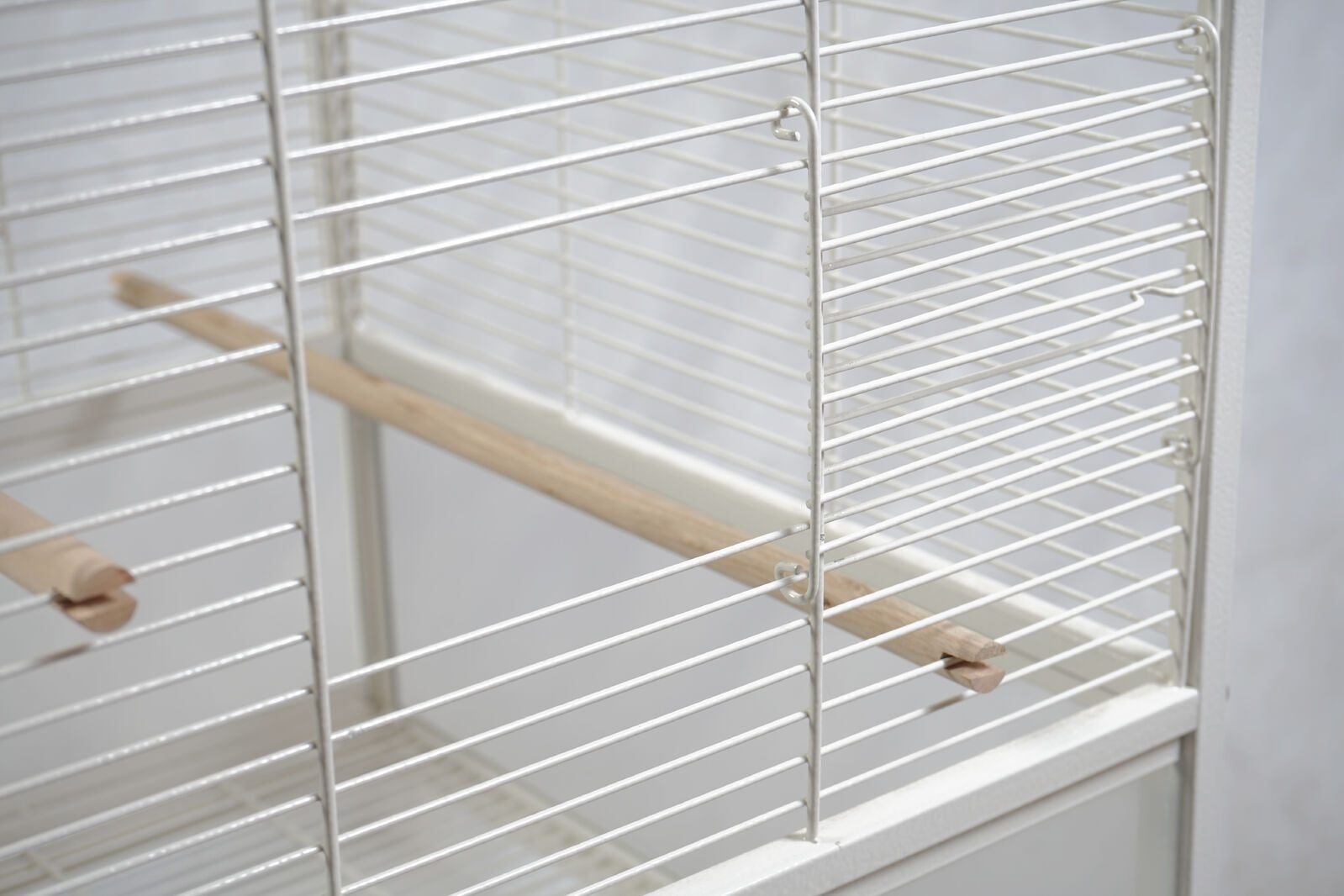 White birdcage with wooden perches on a white background at Pet Servo